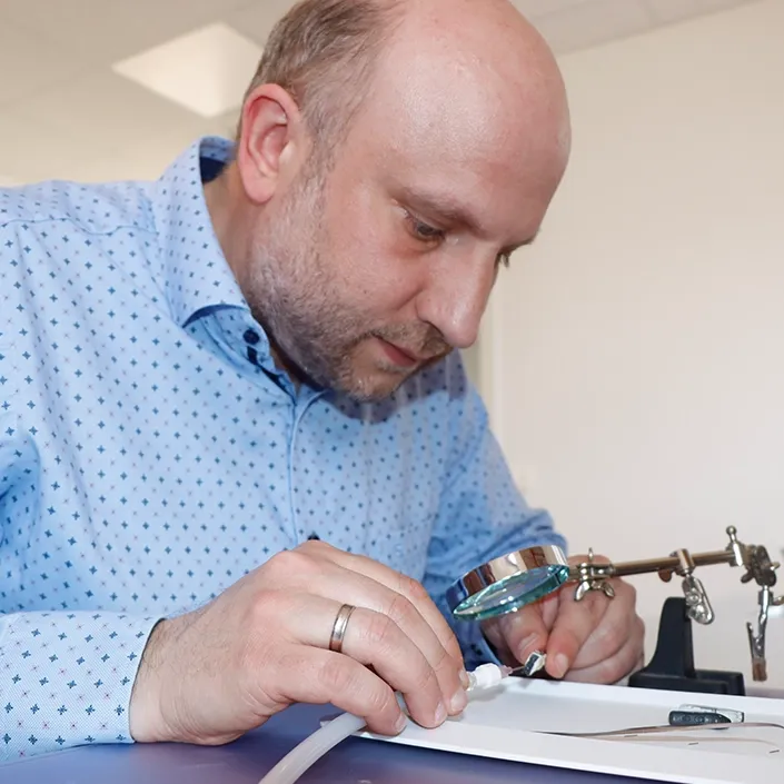 Hörakustiker bei der Reparatur eines Hörgeräts